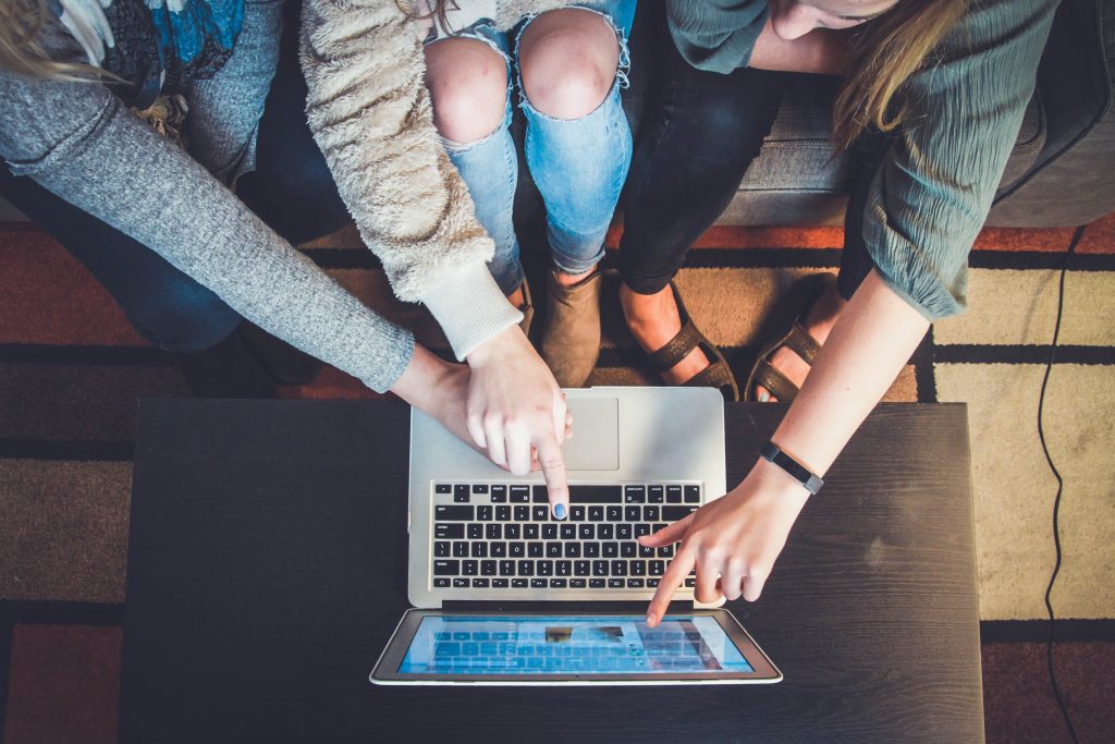 Drei Frauen zeigen auf einen Laptop