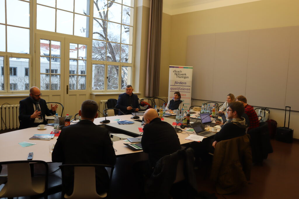 Die Kolleg*innen des Kooperationsnetzwerks OER bei der Arbeit in der Bauhaus-Universität Weimar. Im Hintergrund eine breite Fensterfront und ein Banner des eTeach-Netzwerks Thüringen. 