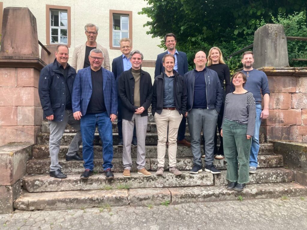 Gruppenfoto der Teilnehmenden der Mitgliederversammlung des Netzwerks der Landeseinrichtungen für digitale Hochschullehre. Die Personen stehen aufgereiht auf einer Treppe und lächeln in die Kamera.