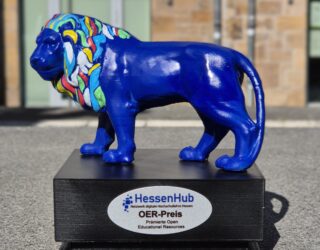 Ein Preis in Form eines bunten Löwens. Auf dem Sockel steht "HessenHub - Netzwerk Digitale Hochschullehre Hessen: OER-Preis. Prämierte Open Educational Resources".