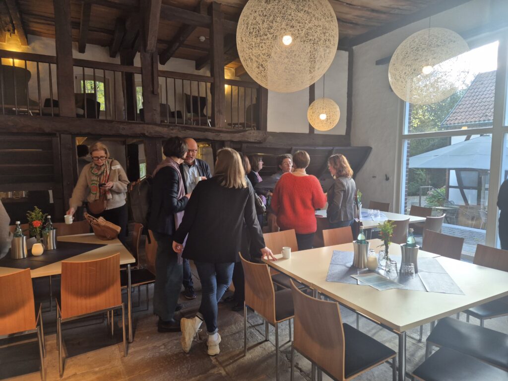 Einige Personen stehen in einem Raum und unterhalten sich in Gruppen.