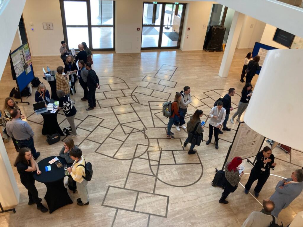 Foto: Einige Personen stehen in einem Foyer und unterhalten sich in Gruppen.